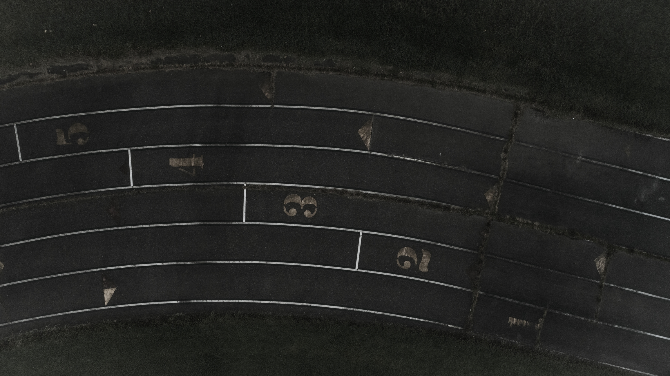 A top-down view of the starting area of a faded outdoor athletics track.