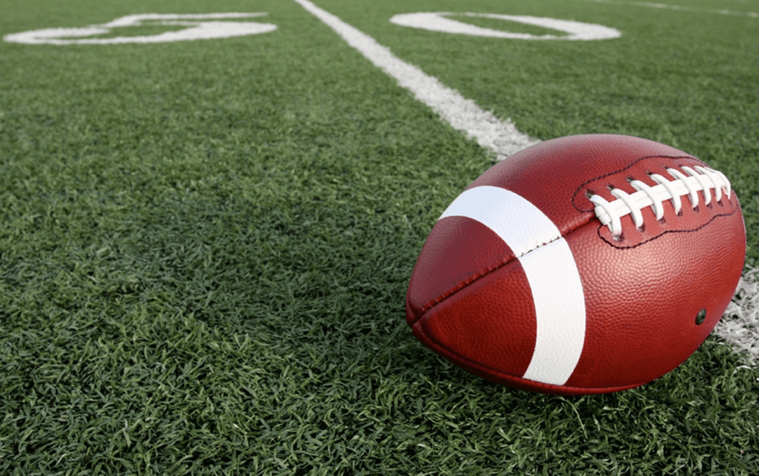 An American Football resting on the 30 yard line.