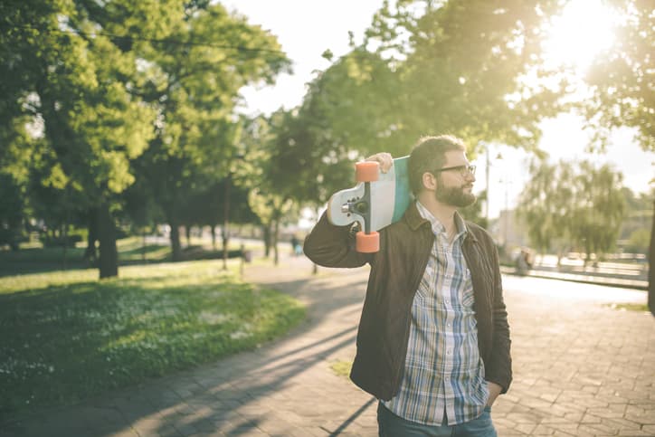 A Scorado Profile picture of a man carrying a longboard on his shoulder while walking.